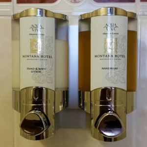 Montana hotel custom hand and body lotion and hand wash dispensers mounted on white wall dispenser amenities